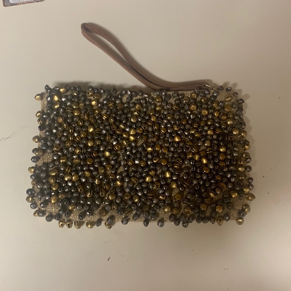Wristlet of Antropologie sizes 5.5”x8.5” . Golden brown color with mini bells.